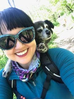 A woman is holding a dog wearing an elf costume.