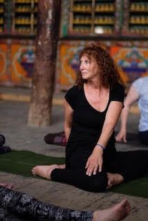 A woman is petting a brown dog in the grass.