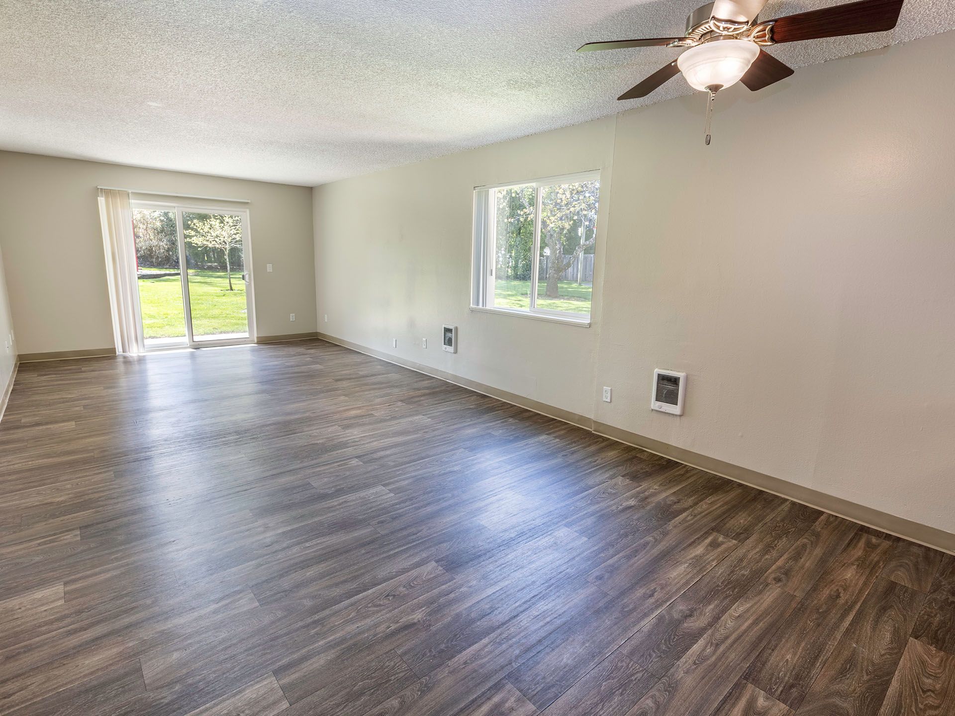 Photo of a long living room, with a ceiling fan, and a sliding glass door
