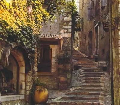 Stone buildings and stairs in a narrow European street, with a restaurant entrance and climbing plants.