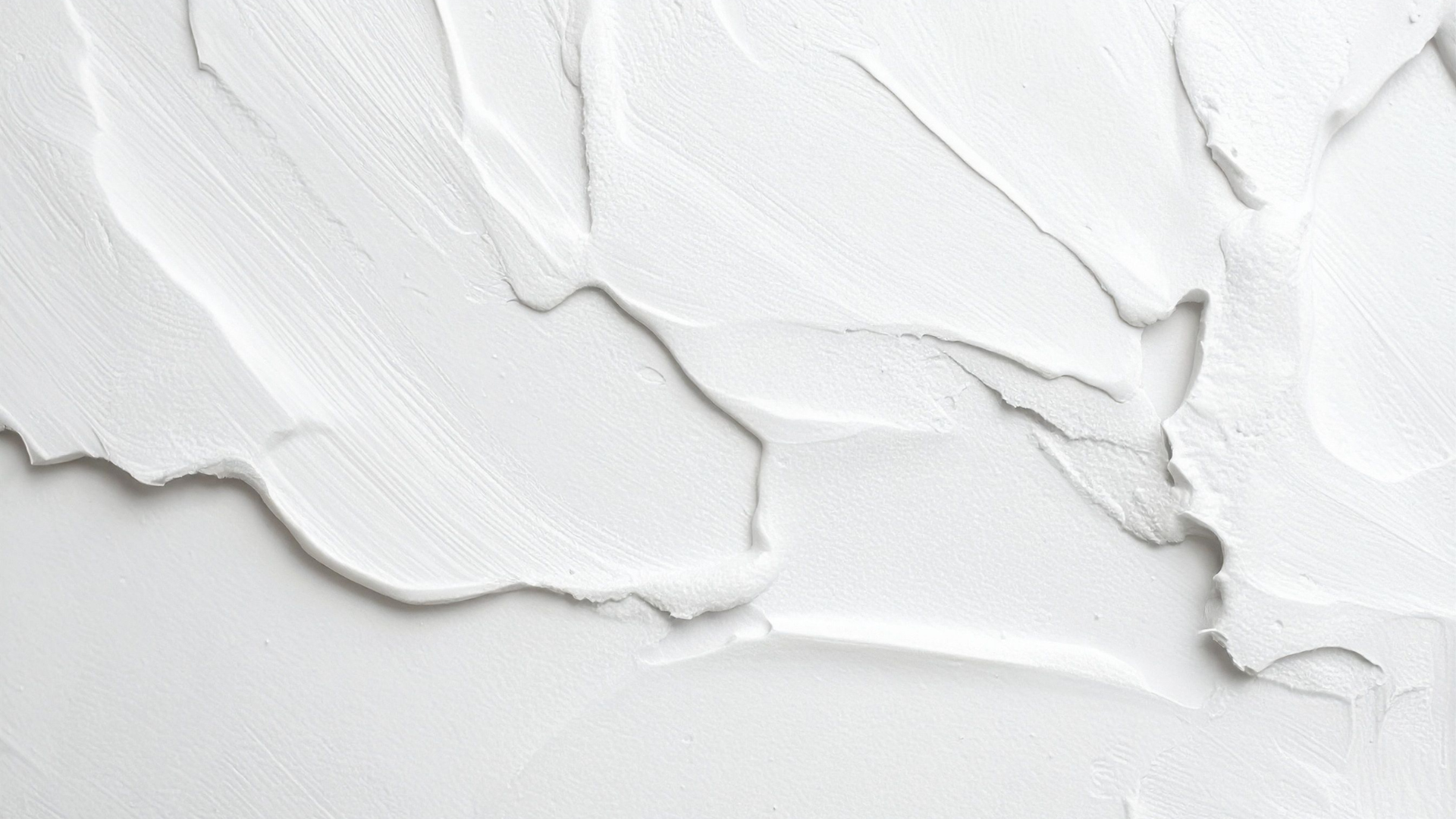 White textured surface with thick, uneven strokes of paint or plaster.