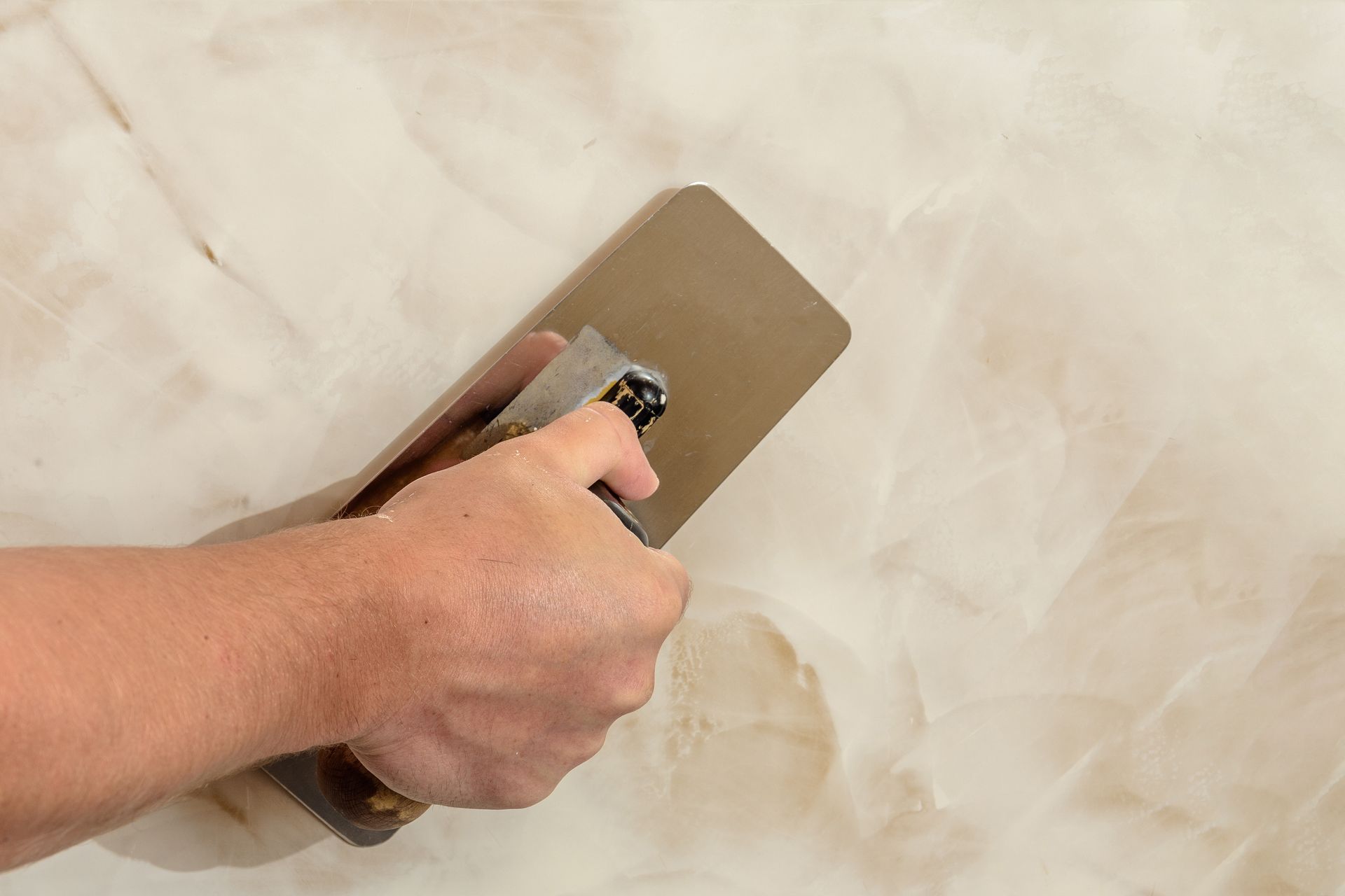 Person using a trowel to apply a decorative stucco finish to a wall.