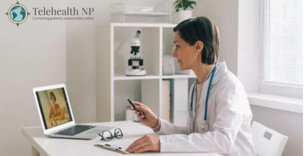 A doctor in a white coat consults with a patient on a laptop, using a stylus and clipboard.