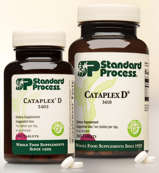 Two bottles of Standard Process Cataplex D dietary supplements, one smaller and one larger, with tablets in front.