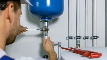 A man is fixing a water heater with a wrench.