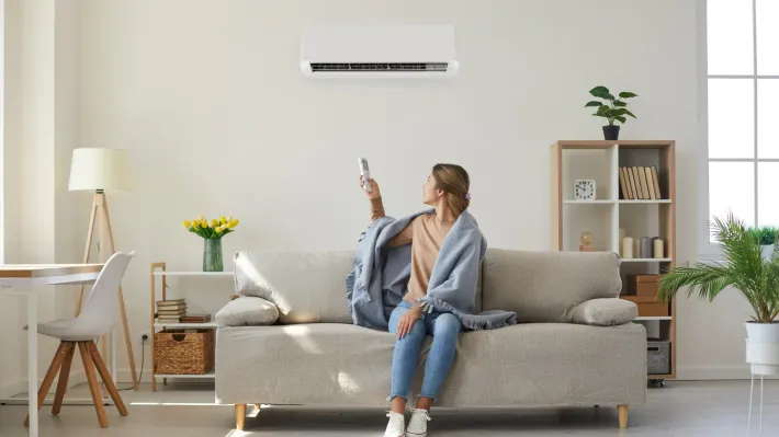 A woman is sitting on a couch holding a remote control.
