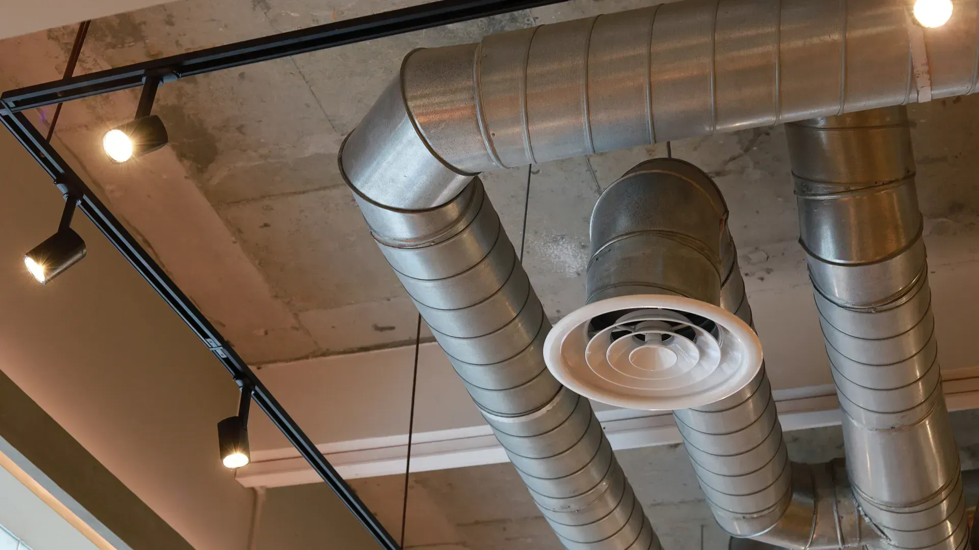 A bunch of metal pipes are hanging from the ceiling of a building.