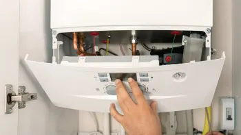 A person is working on a boiler in a kitchen.