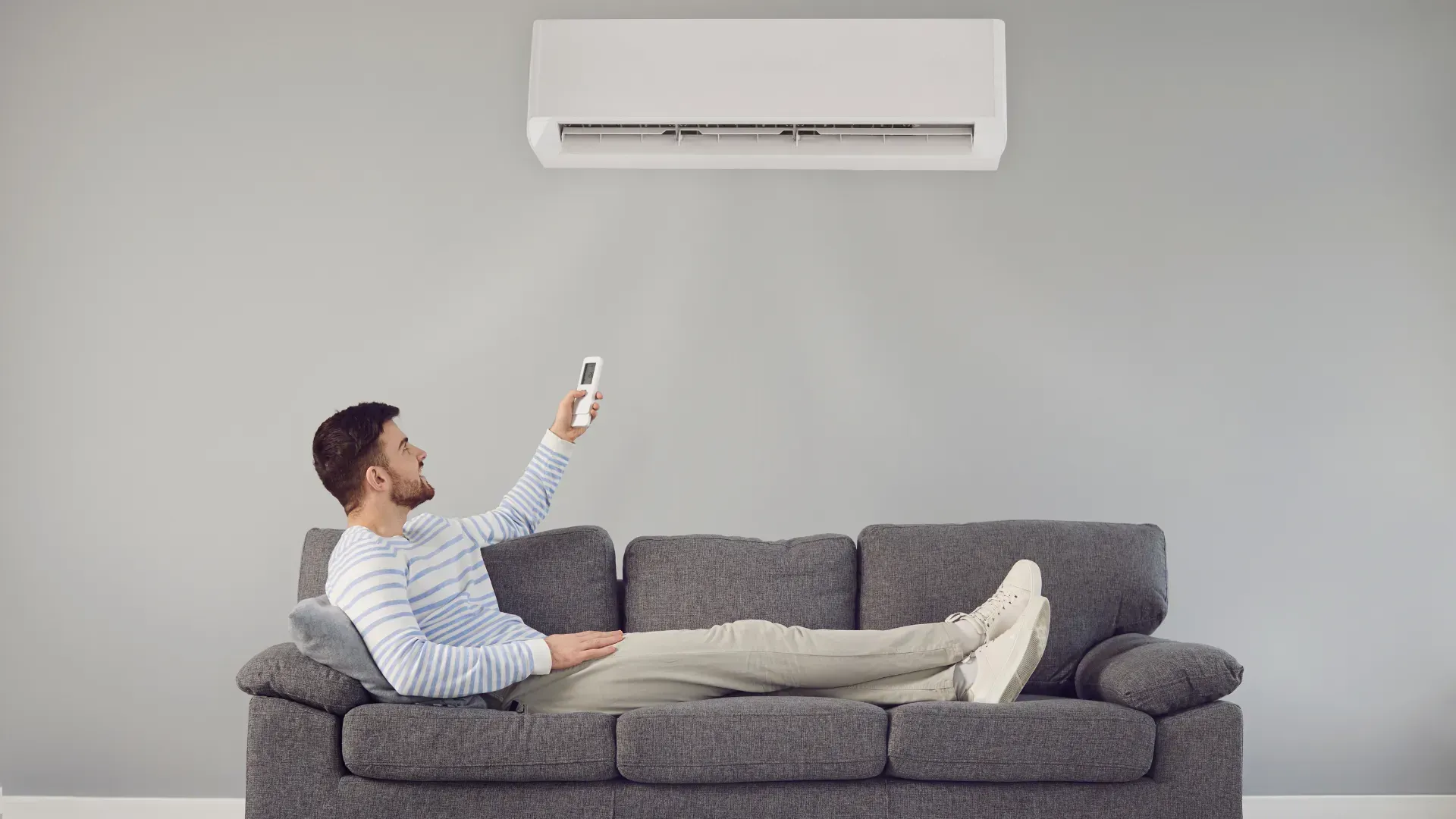 A man is sitting on a couch holding a remote control.