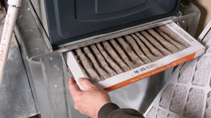 A person is cleaning a filter on a furnace.