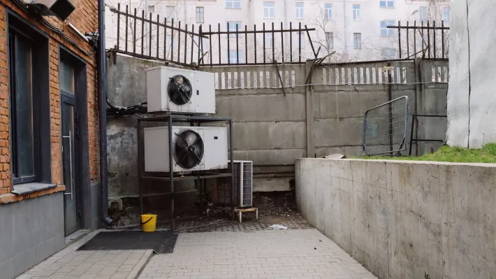 There are a lot of air conditioners on the side of a building.