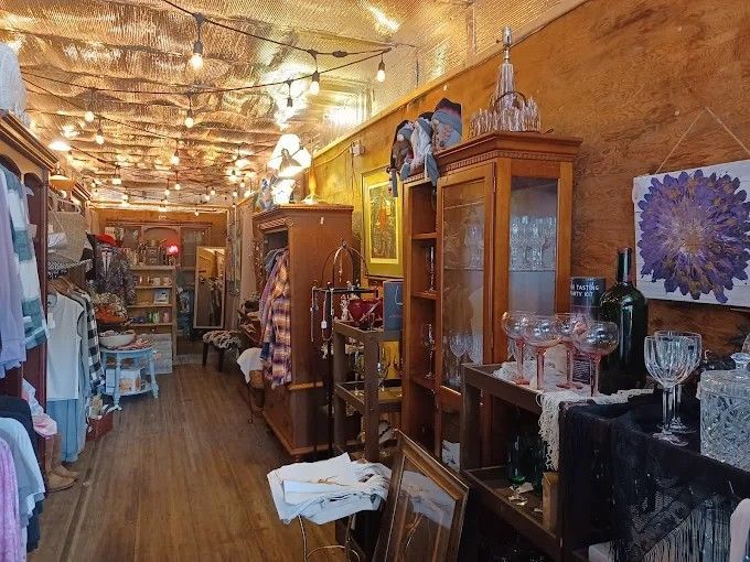 Clothing on a rack inside a dimly lit boutique with a textured ceiling, string lights, and a hanging sale sign.