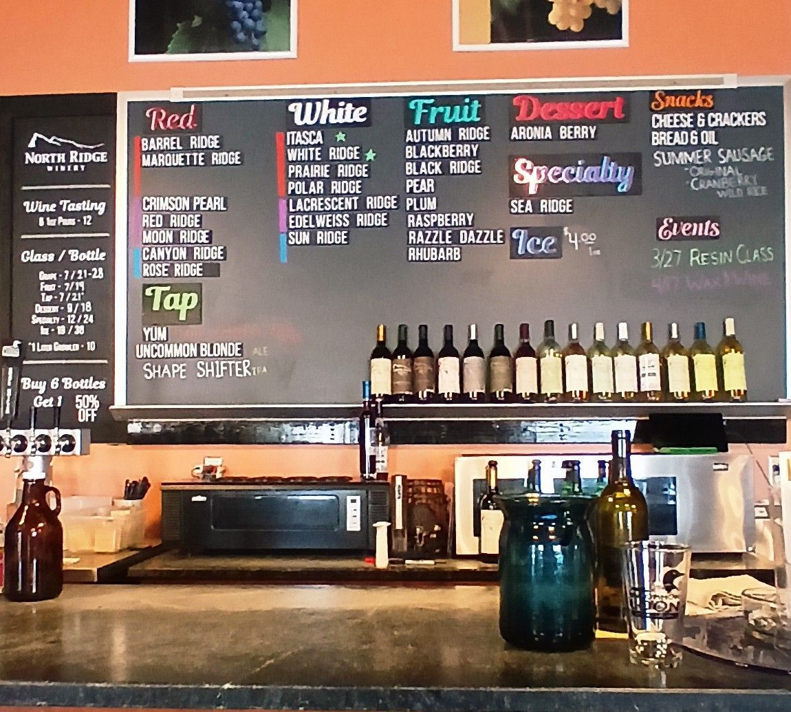 Dimly lit restaurant interior with dark wooden walls, multiple round tables, and black chairs.