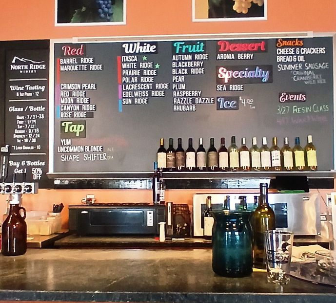 Dimly lit restaurant interior with dark wooden walls, multiple round tables, and black chairs.