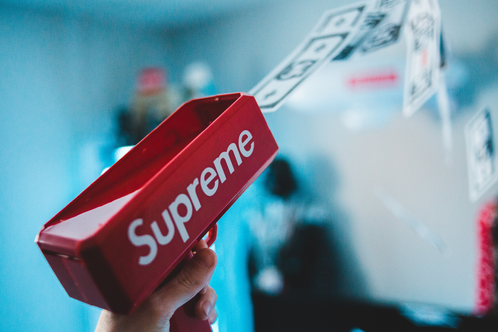 A person is holding a red box that says supreme on it