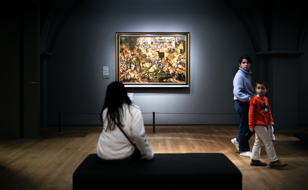 A woman sits on a bench in front of a painting