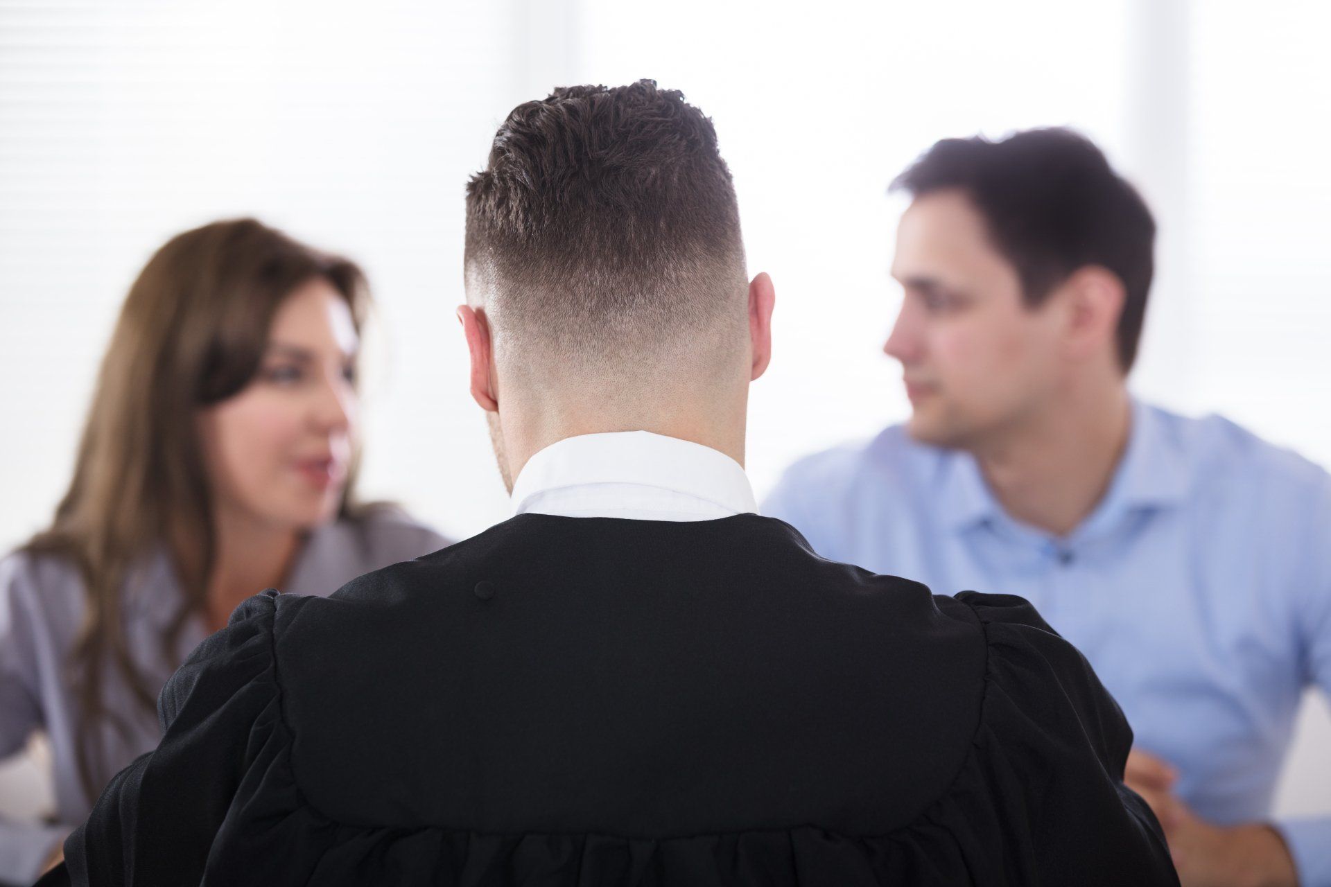A lawyer in black robe consults with a couple in an office.
