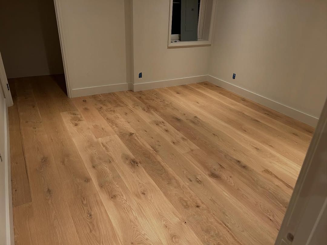 A bedroom with hardwood floors and white walls.