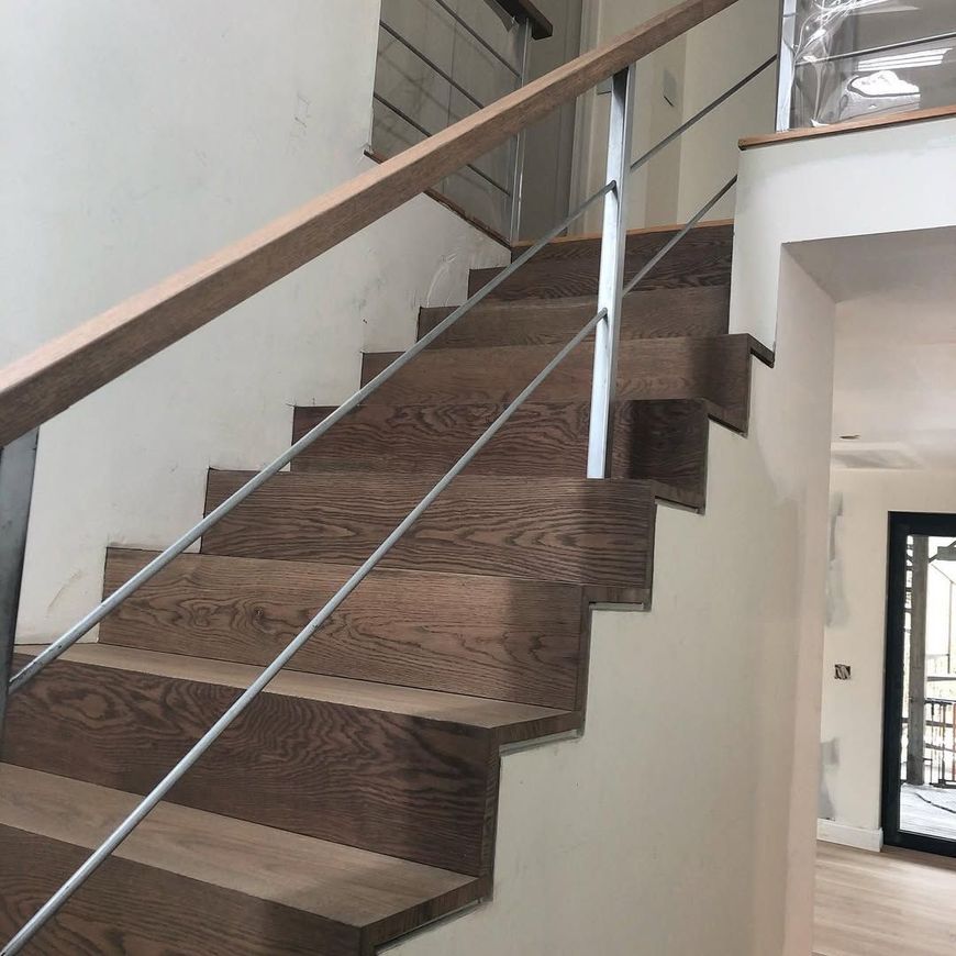 A set of wooden stairs with a metal railing