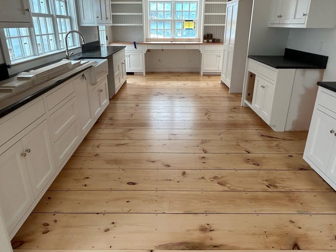 A kitchen with wooden floors and white cabinets.