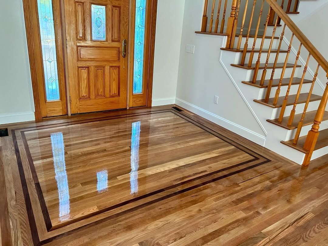 A wooden floor with a rug on it in a room with stairs.