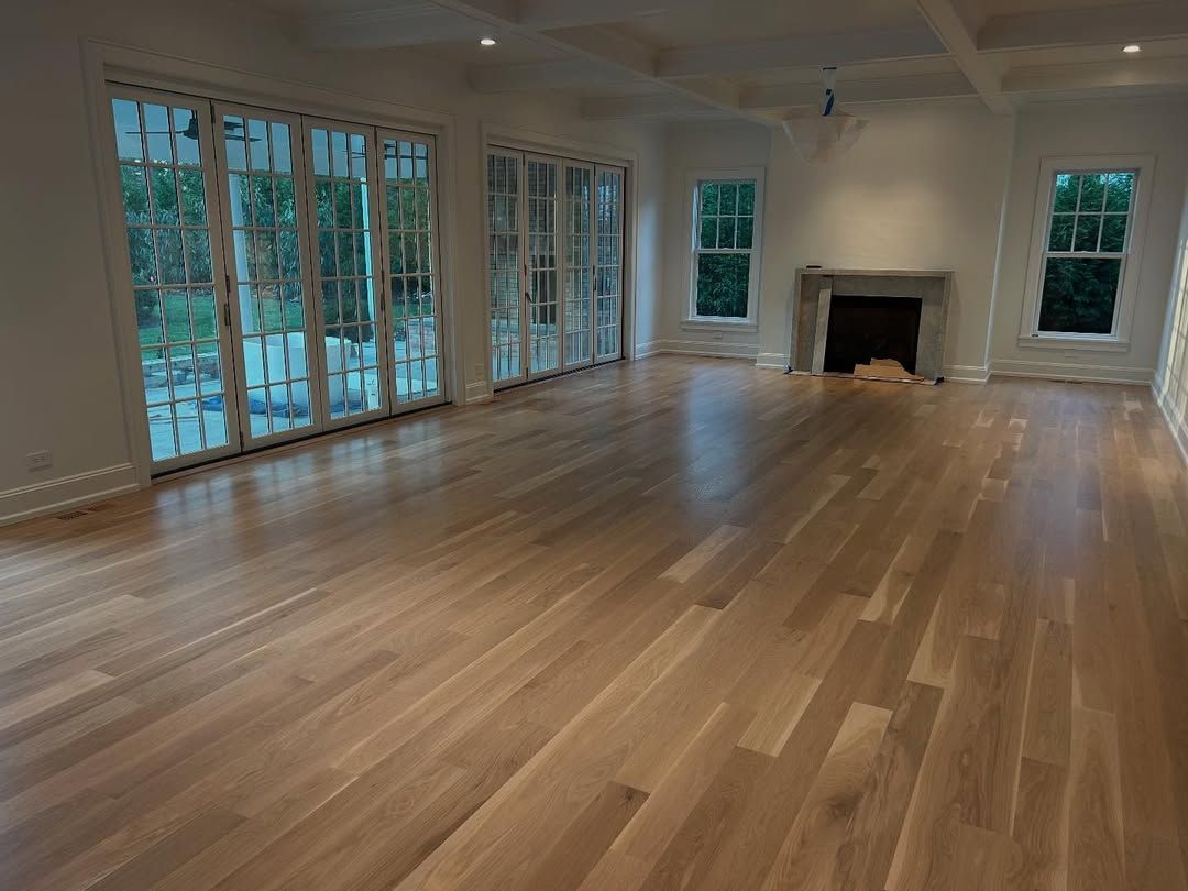 An empty living room with hardwood floors and a fireplace.