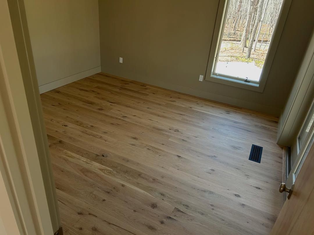 An empty room with hardwood floors and a window.