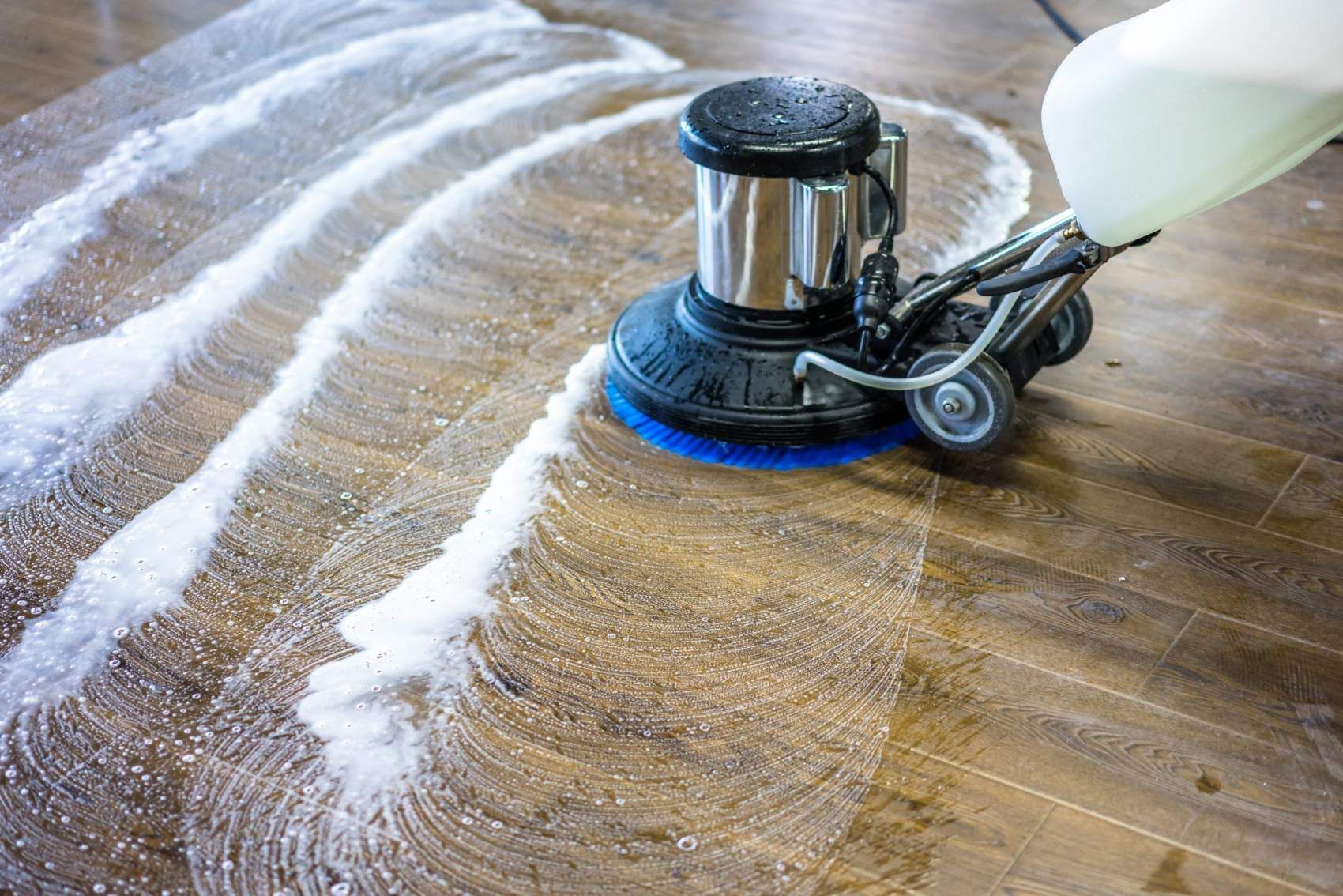 A person is using a machine to clean a wooden floor.