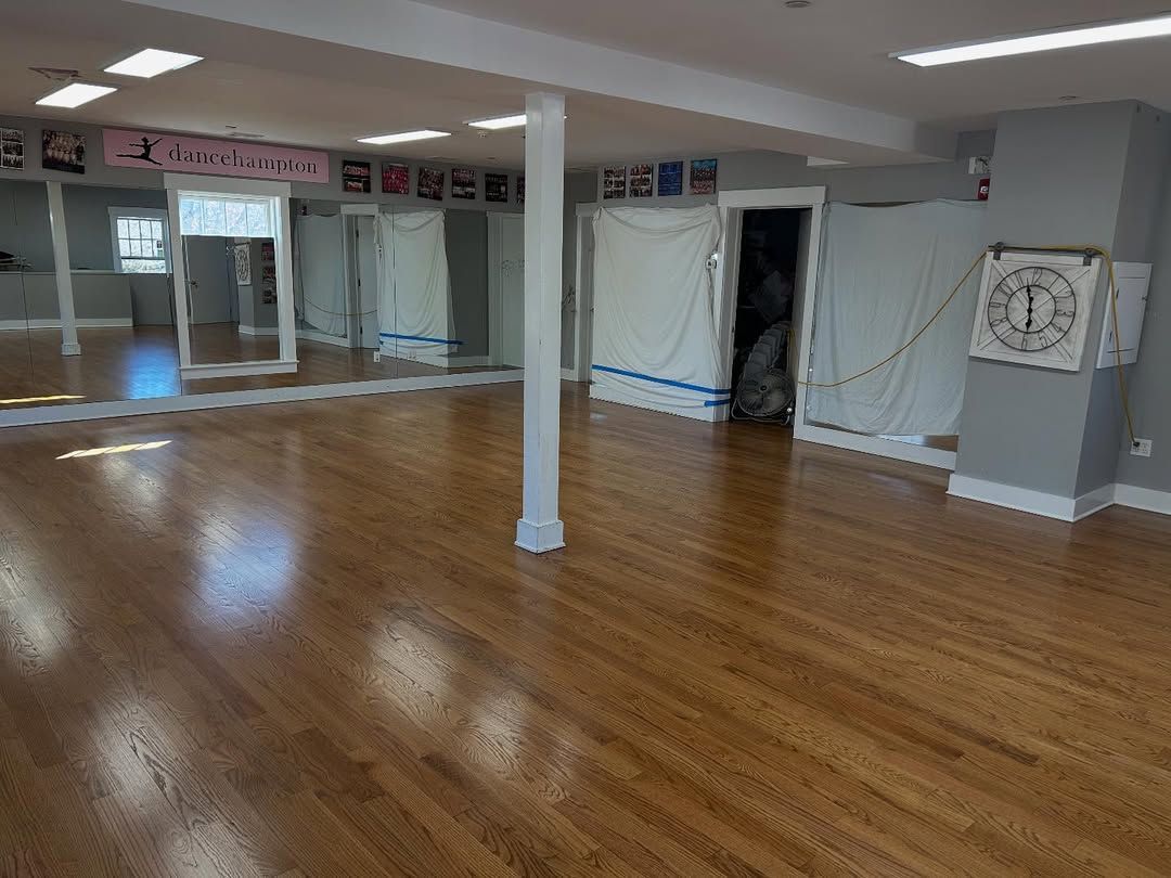 A large empty room with wooden floors and mirrors.