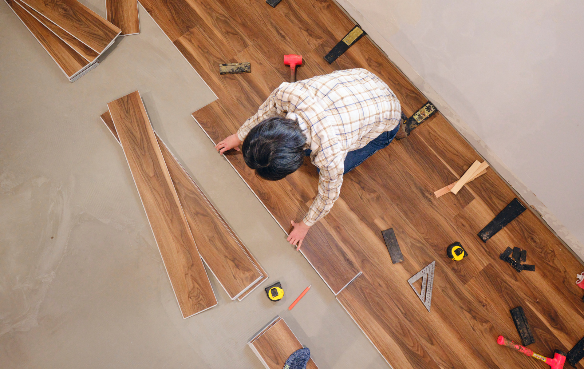 A man is installing a wooden floor in a room.