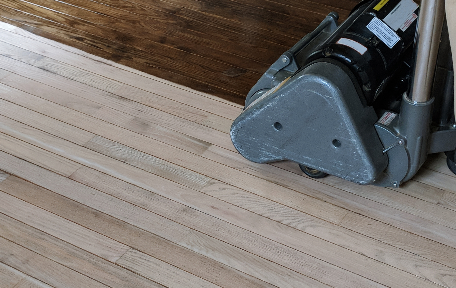 A machine is being used to sand a wooden floor