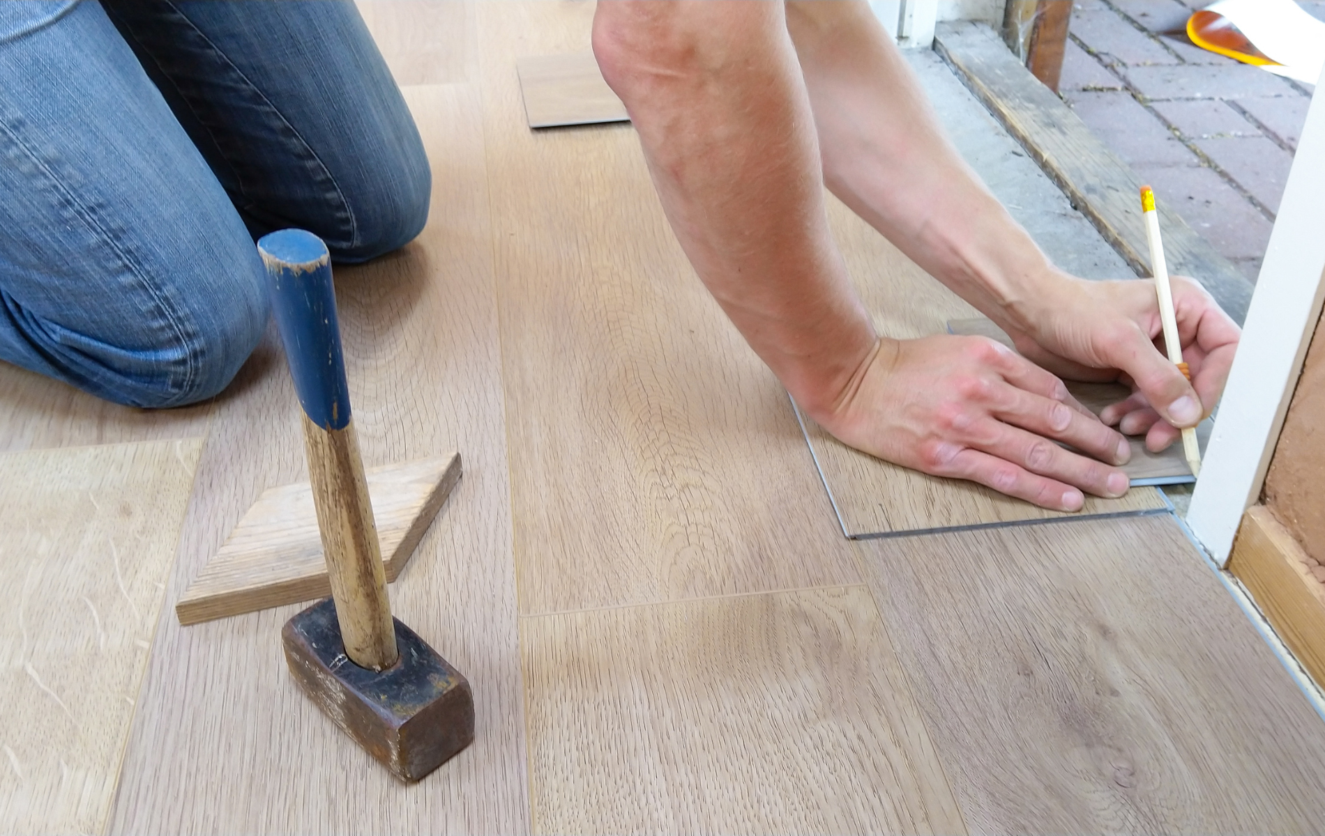 A person is measuring a piece of wood with a hammer.