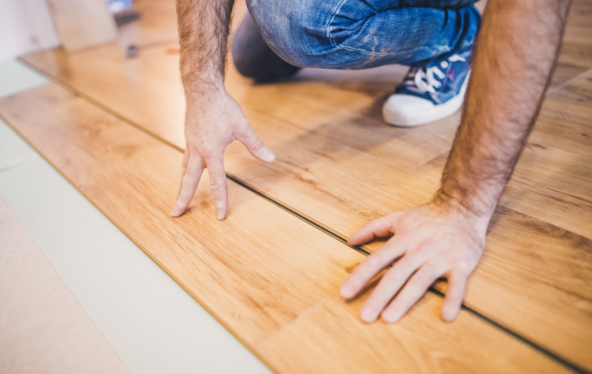 A man is installing a wooden floor in a room.