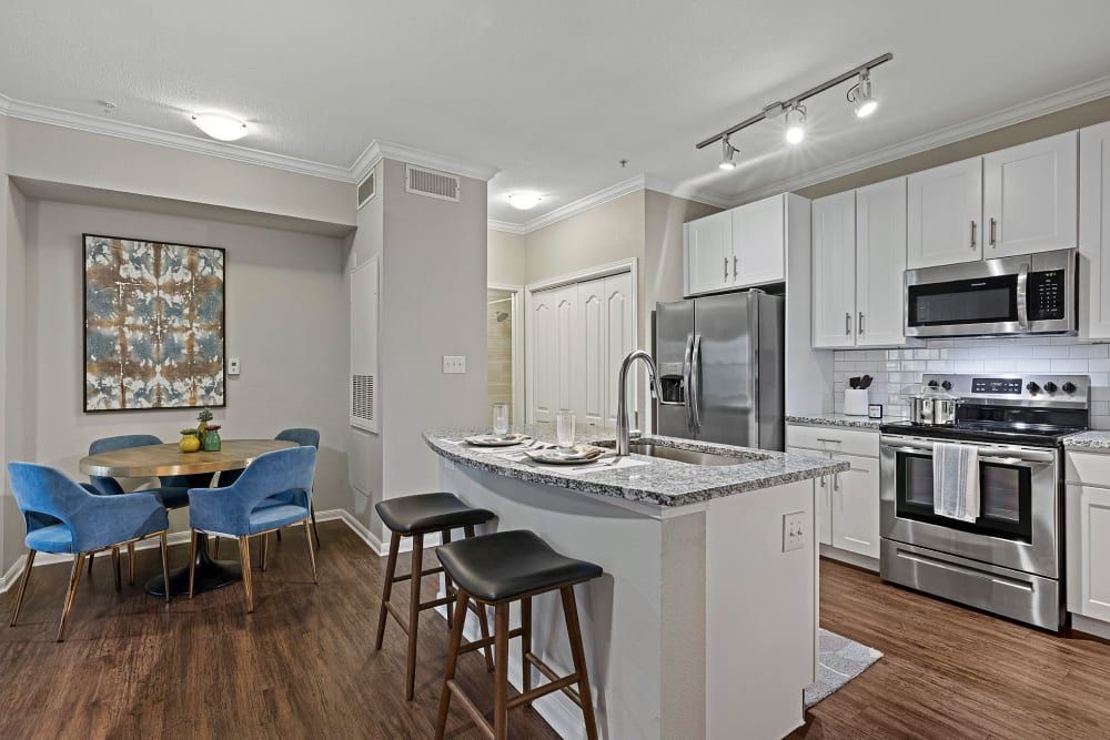 a kitchen with white cabinets and stainless steel appliances and a dining room with a table and chairs at Marquis Parkside in Austin, TX.