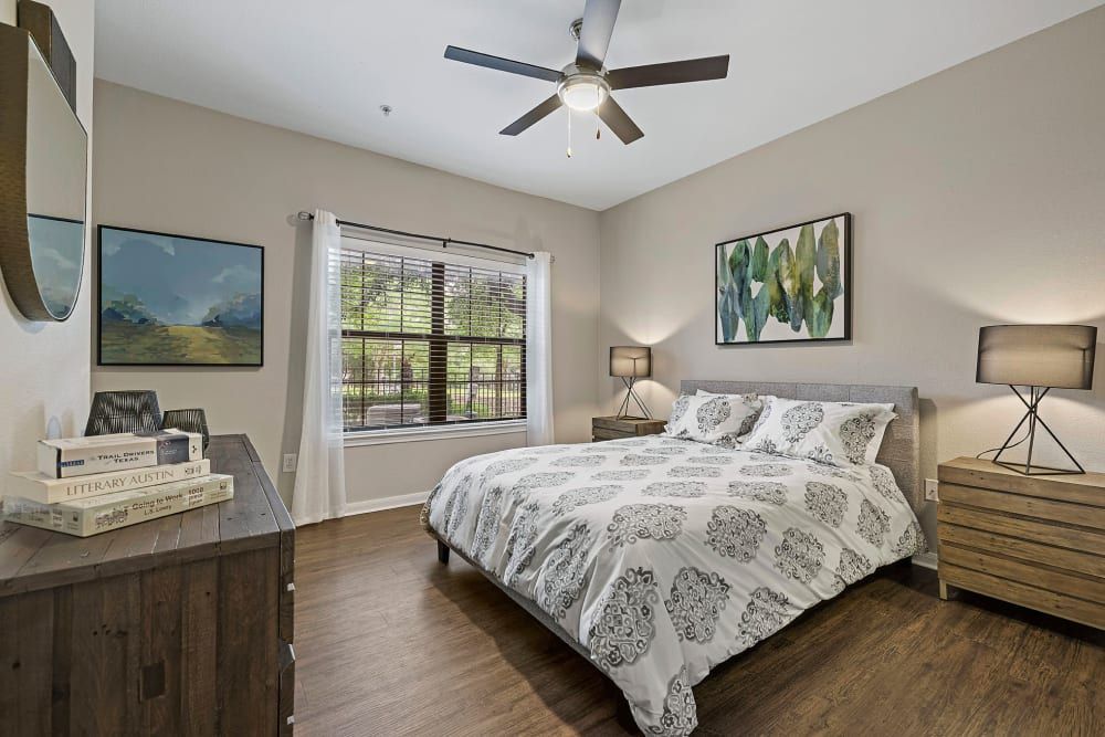 a bedroom with a bed, dresser, nightstand, and ceiling fan at Marquis Parkside in Austin, TX.