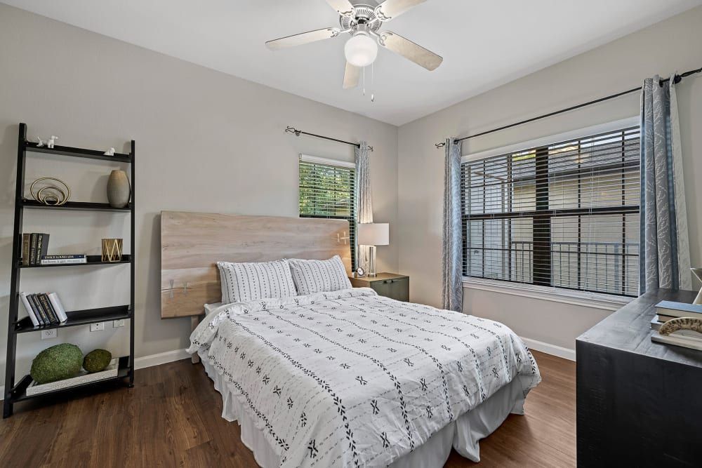a bedroom with a bed, ceiling fan, dresser, and window at Marquis Parkside in Austin, TX.