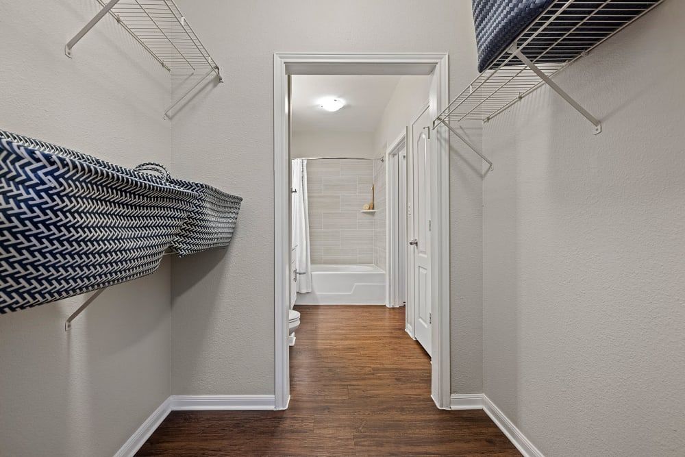 a walk-in closet with lots of shelves and a door leading to a bathroom at Marquis Parkside in Austin, TX.