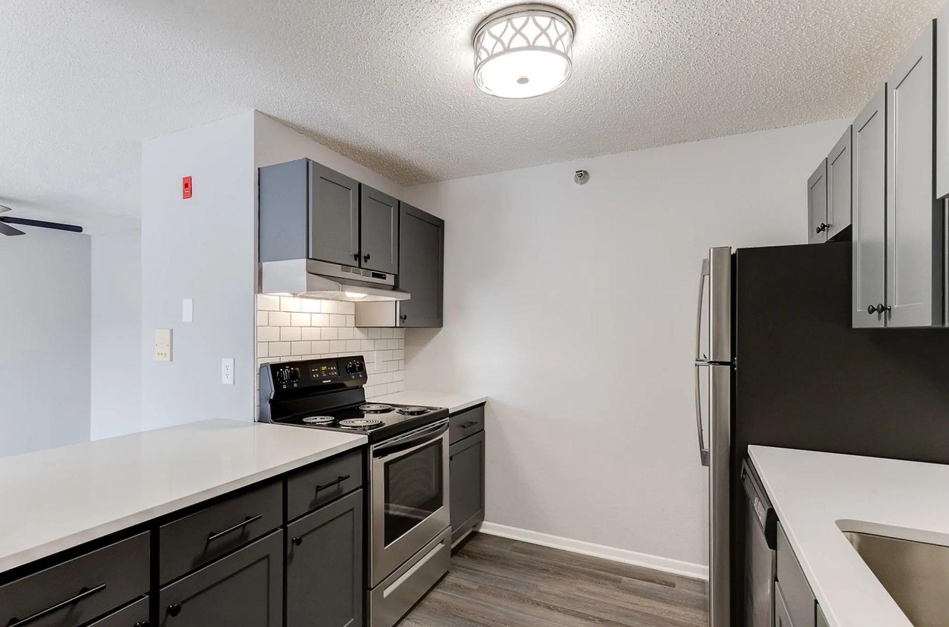 Kitchen with gray cabinets, white countertops, stainless steel appliances, and a white brick backsplash.