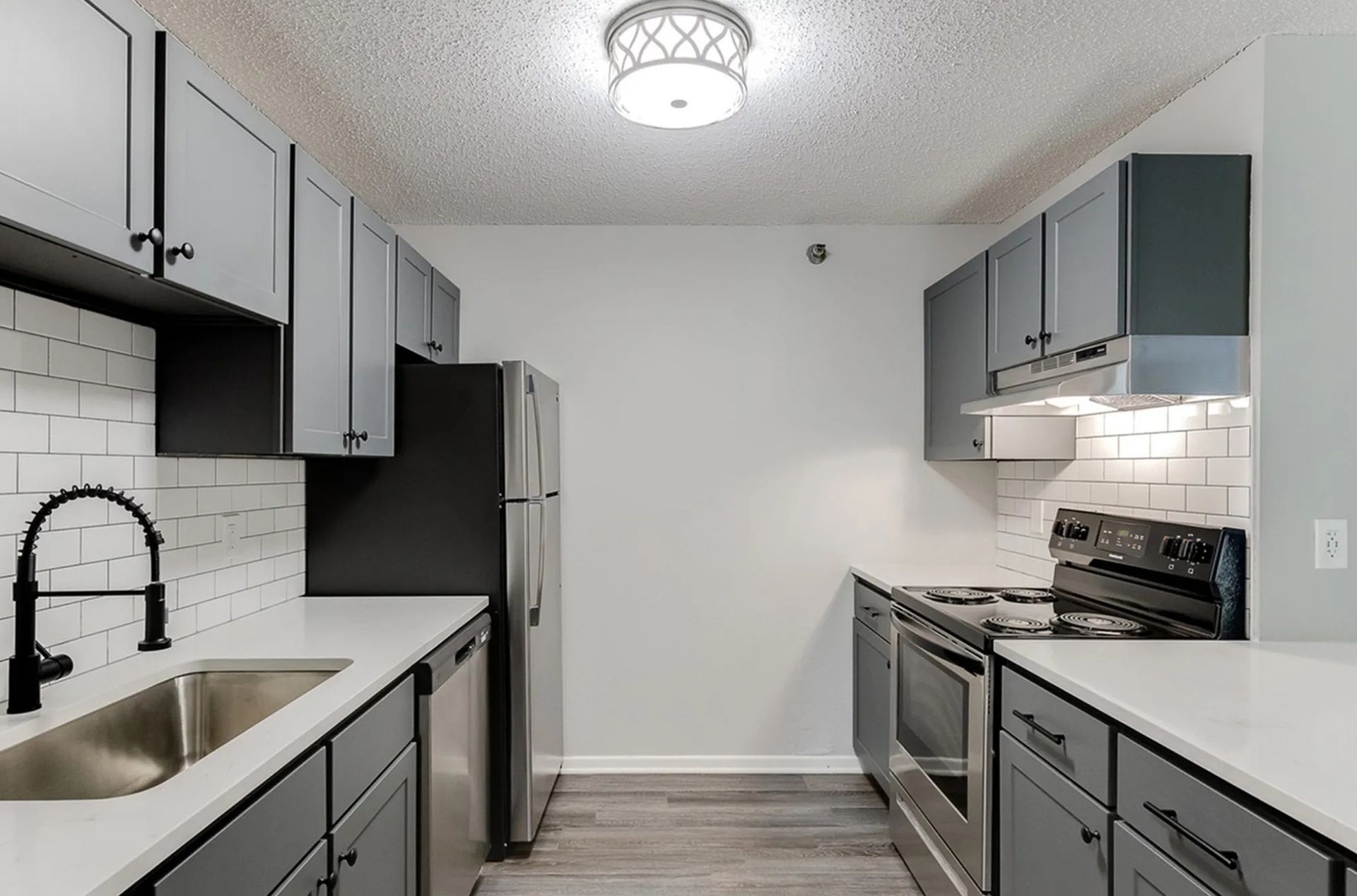 Gray kitchen with white countertops, stainless steel appliances, and white subway tile backsplash.