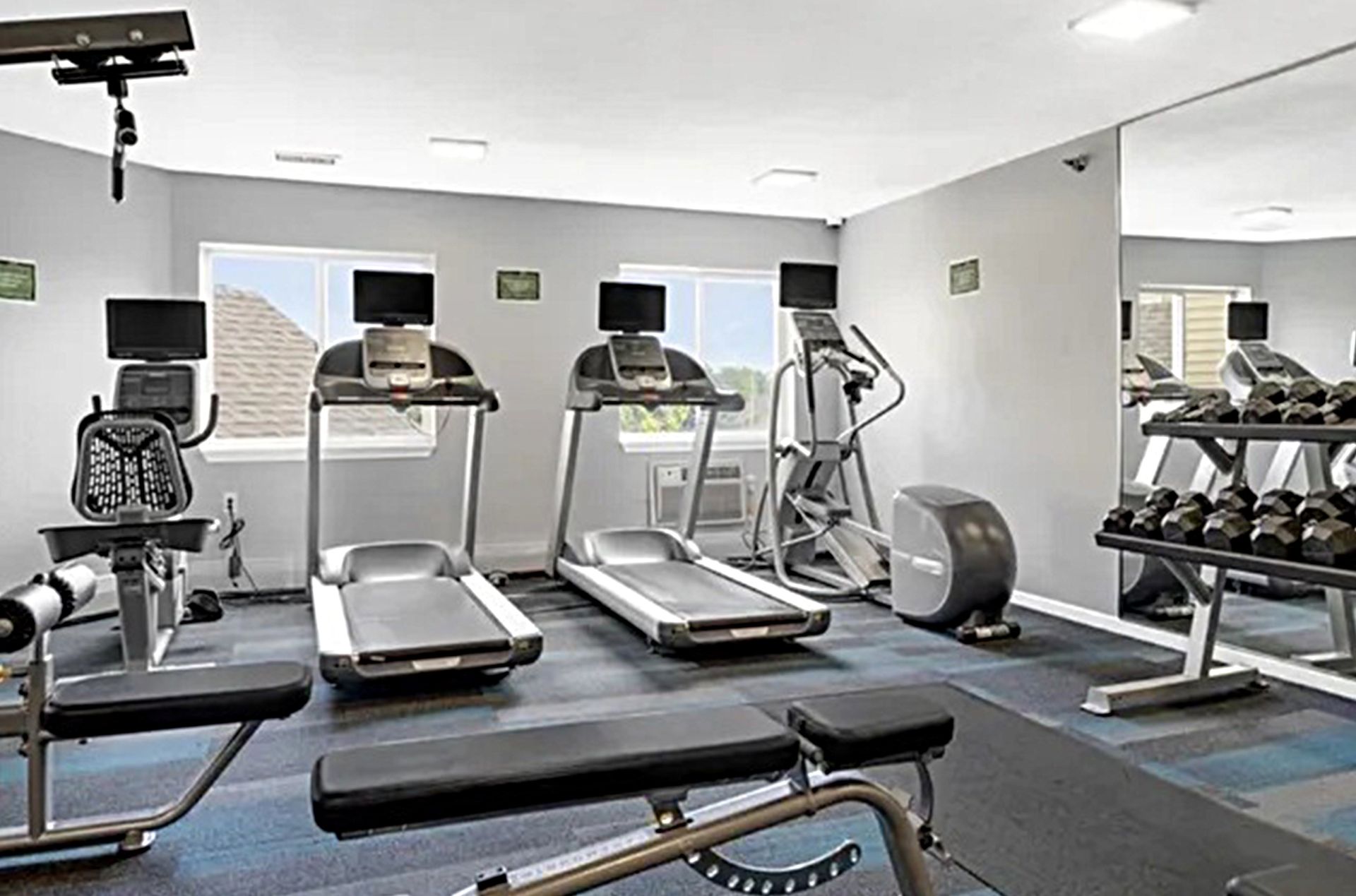 Gym with treadmills, elliptical, weights, and exercise bench.