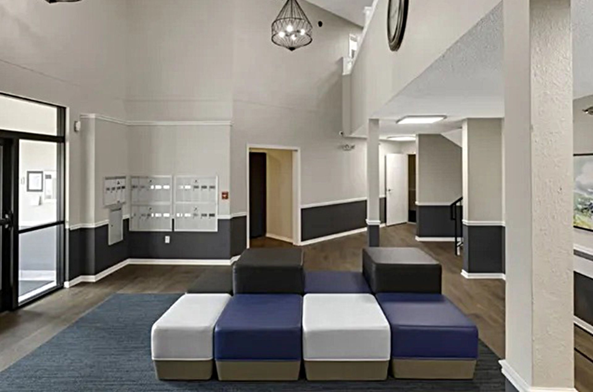 Lobby with modular seating, mailboxes, and dark gray and white walls. A door is visible.