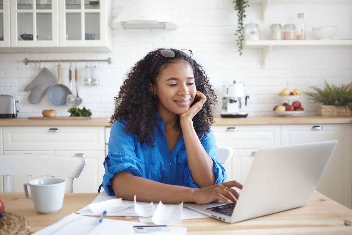 A woman is holding a credit card while using a laptop computer.