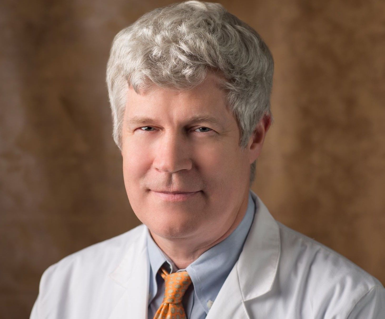 A man wearing a white coat and orange tie