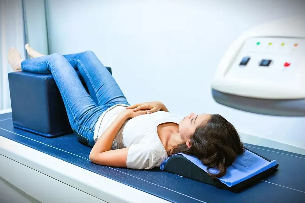 A woman is laying on a bed getting an x-ray of her stomach.