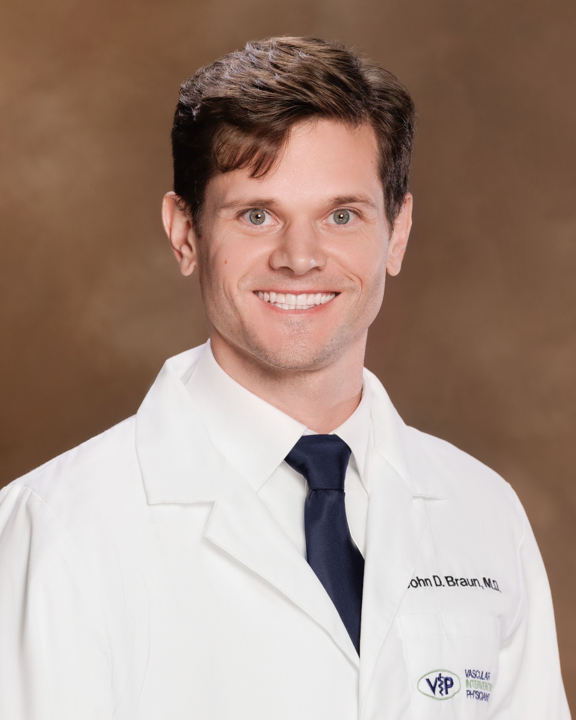 A man in a white coat and tie is smiling for the camera.