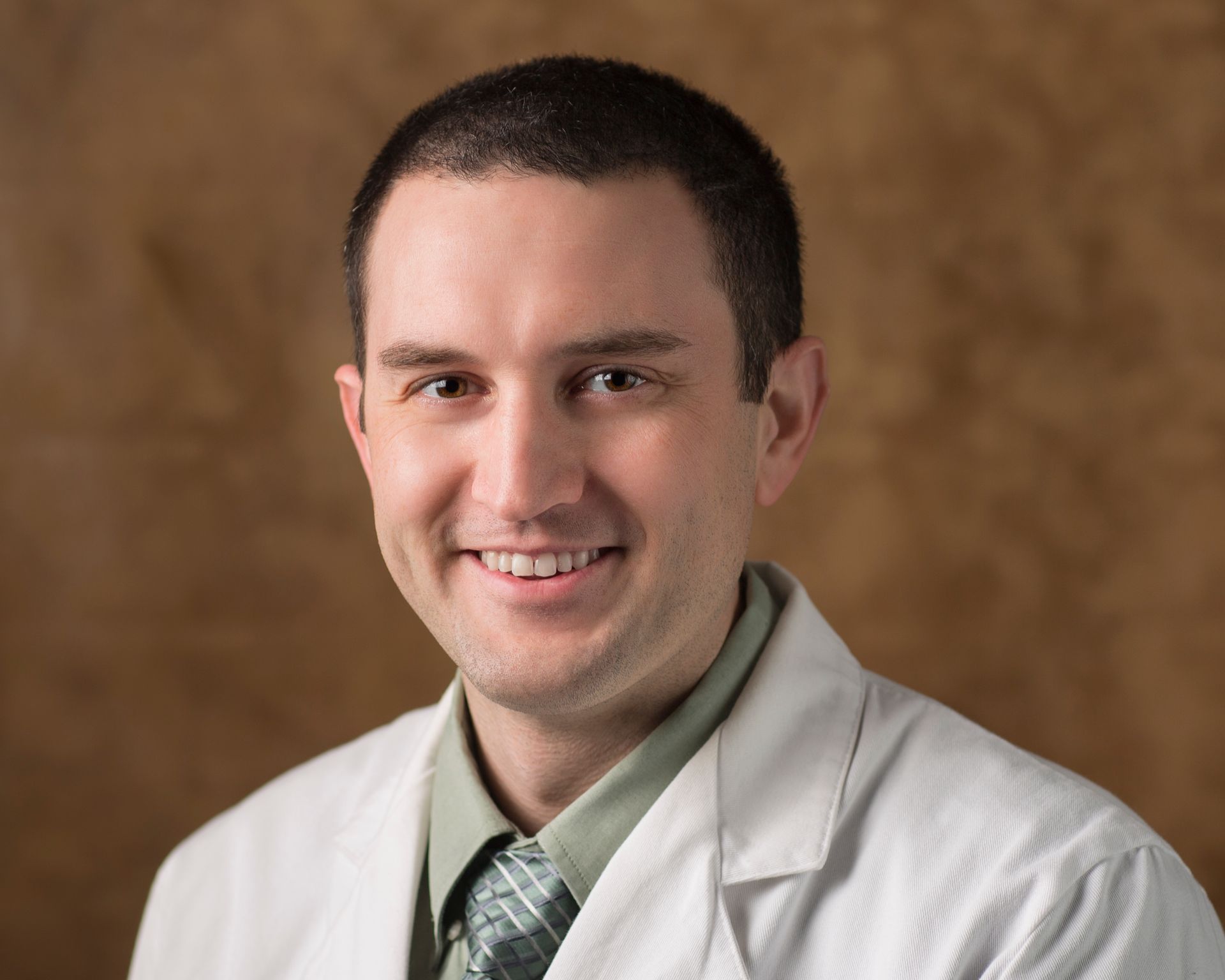 A man in a white coat and tie is smiling for the camera