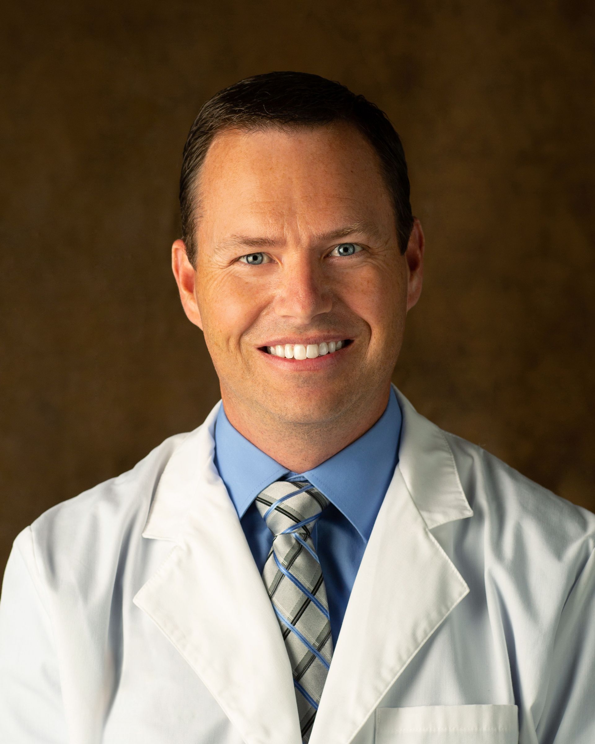 A smiling doctor wearing a white coat and tie