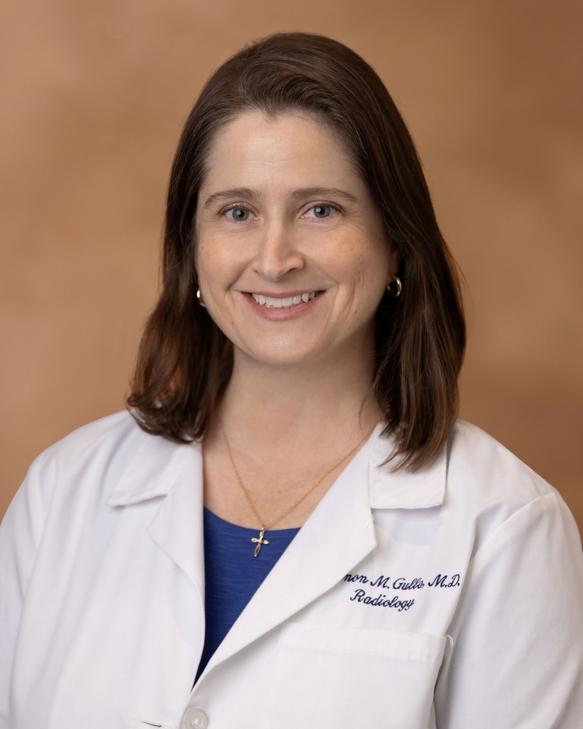 A woman in a white lab coat is smiling for the camera