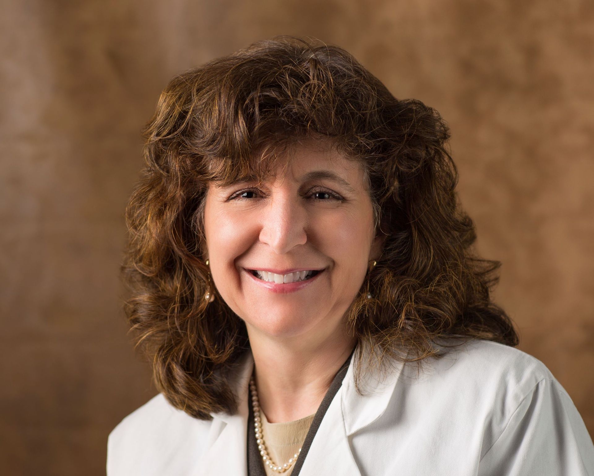 A woman in a white lab coat is smiling for the camera.