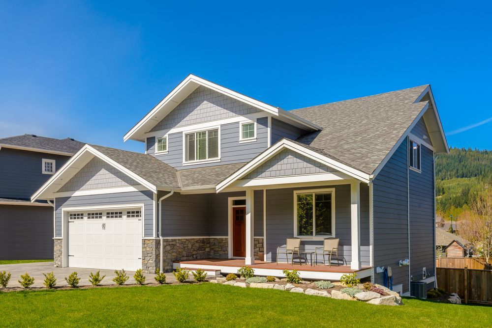 A large gray house with a white garage door and a porch.